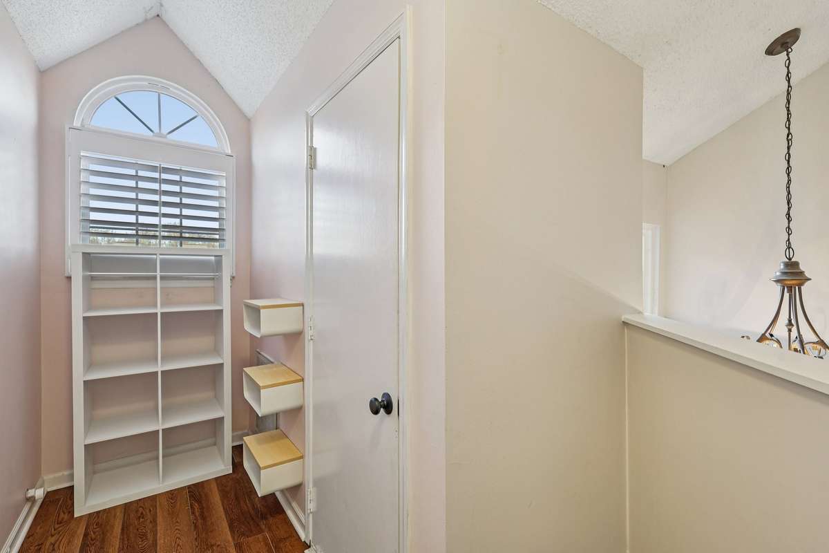 Charming upper-level nook with vaulted ceiling and arched window – perfect for a reading corner, small office, or stylish display. Built-in shelving offers great storage potential.