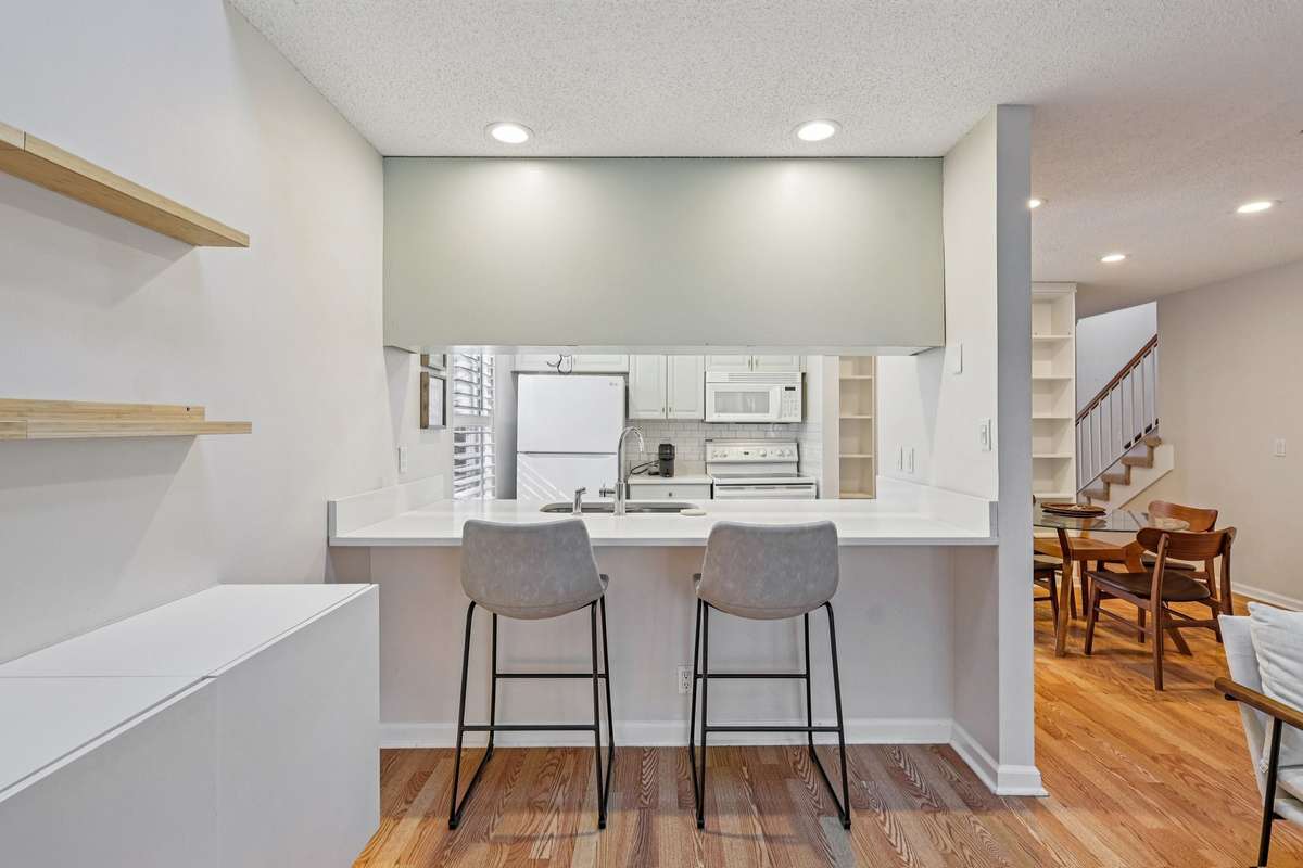 Casual bar seating at the peninsula, perfect for morning coffee, quick meals, or extra prep space. Full view of the kitchen, dining area, and living room.