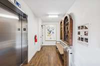 Interior hallway to front door with elevator.