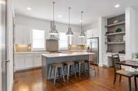 Soft natural light streams into this elevated kitchen with quartz, tile backsplash and stainless steel appliances. The large island and breakfast bar is always a favorite, and there is even space for a desk!