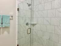 A beautiful, frameless shower is located in the primary bathroom