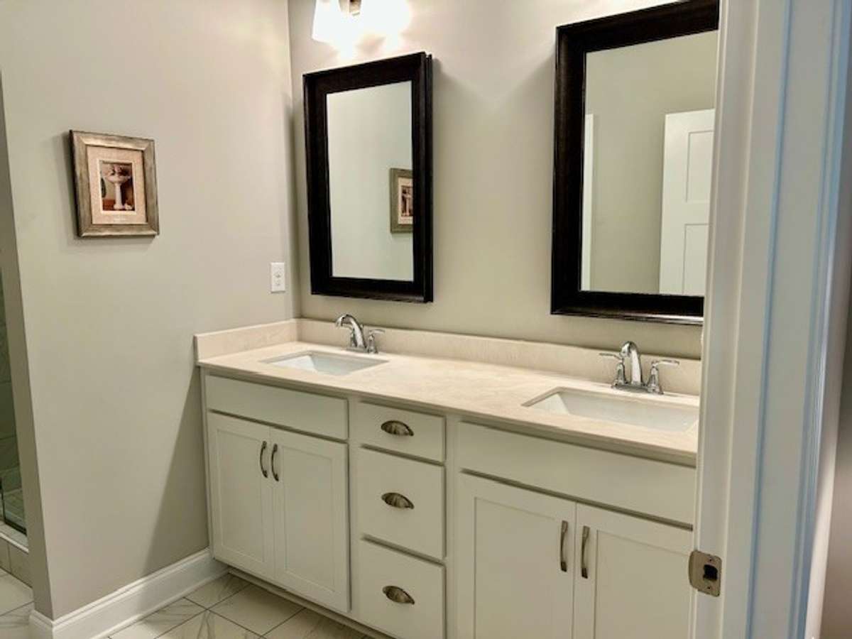 The primary bathroom is spacious with double vanities and has a ceramic tile floor.