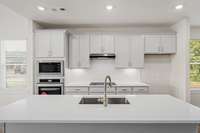 Chic subway tile backsplash, beautiful quartz countertops, and a venthood above the cooktop that vents to the exterior.