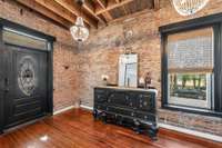 Gorgeous chandeliers, exposed brick, and refinished original hardwood floors greet you in the entrance foyer.