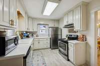 Updated kitchen includes painted cabinetry with new hardware and new countertops