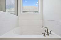 Relax and recharge in the soaking tub. Surrounded by tilework and positioned beneath a large window for natural light, this tub offers the perfect retreat for unwinding after a long day.