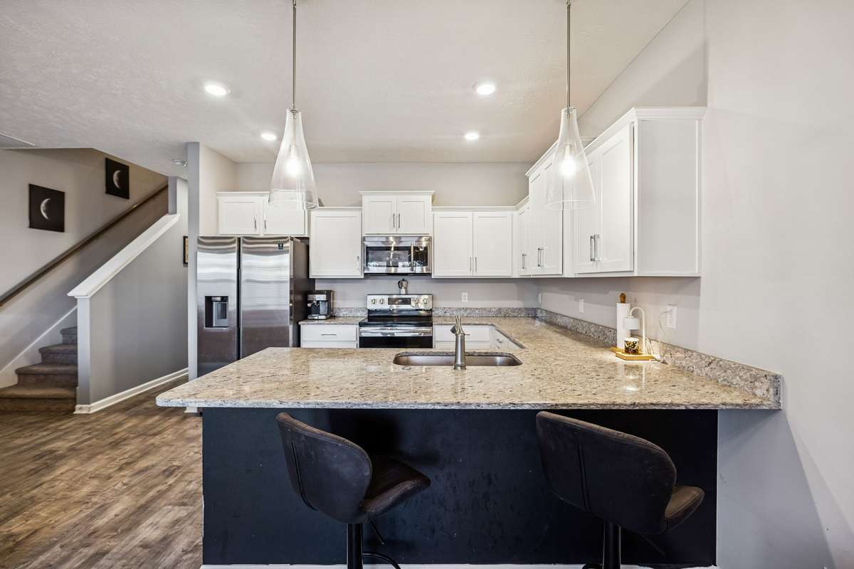 Another view of the kitchen-SS appliances, white cabinetry, and beautiful granite countertops.