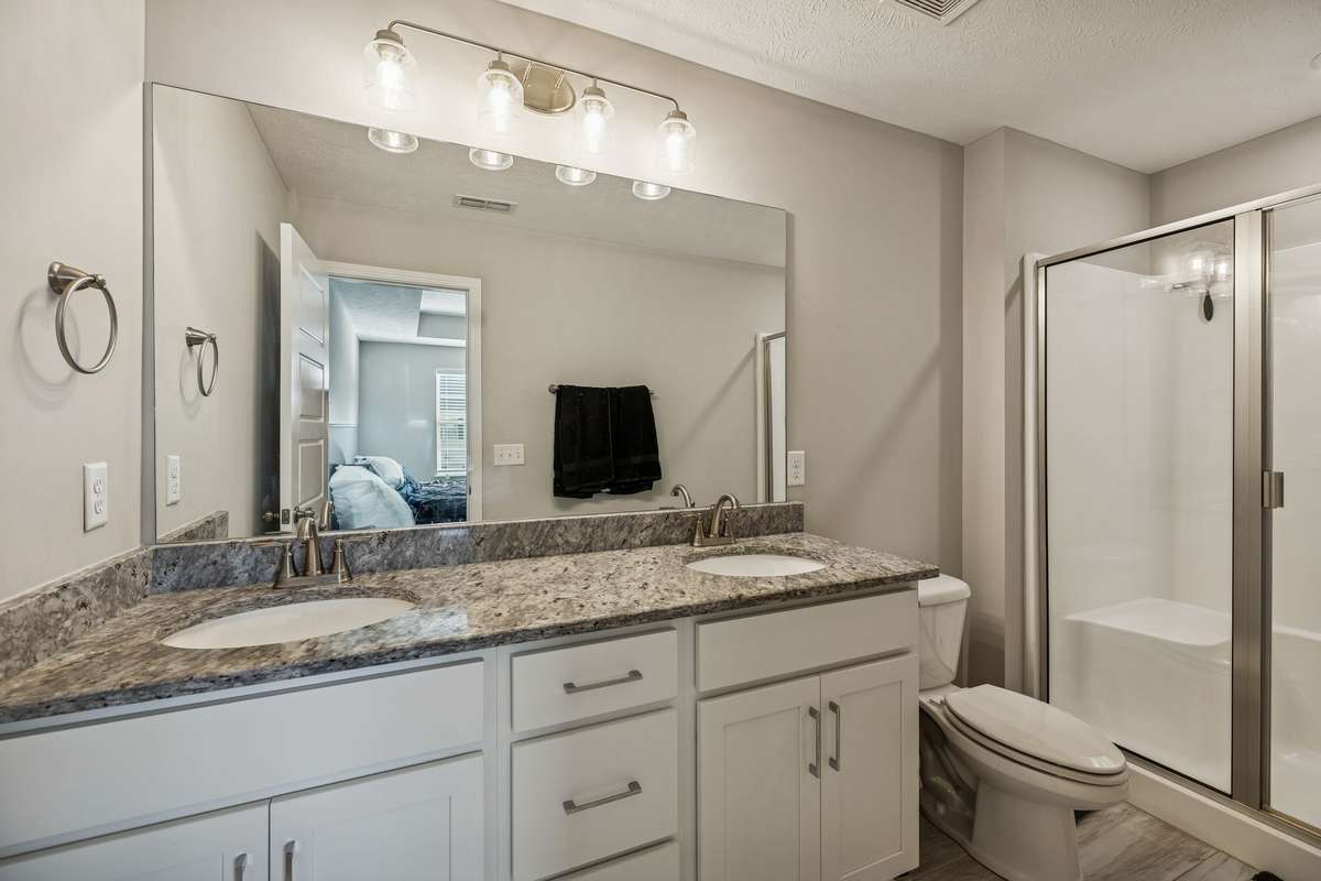 The primary bathroom has double sinks and a large walk-in shower. The lovely granite counter tops seen downstairs are also featured in the bathrooms.