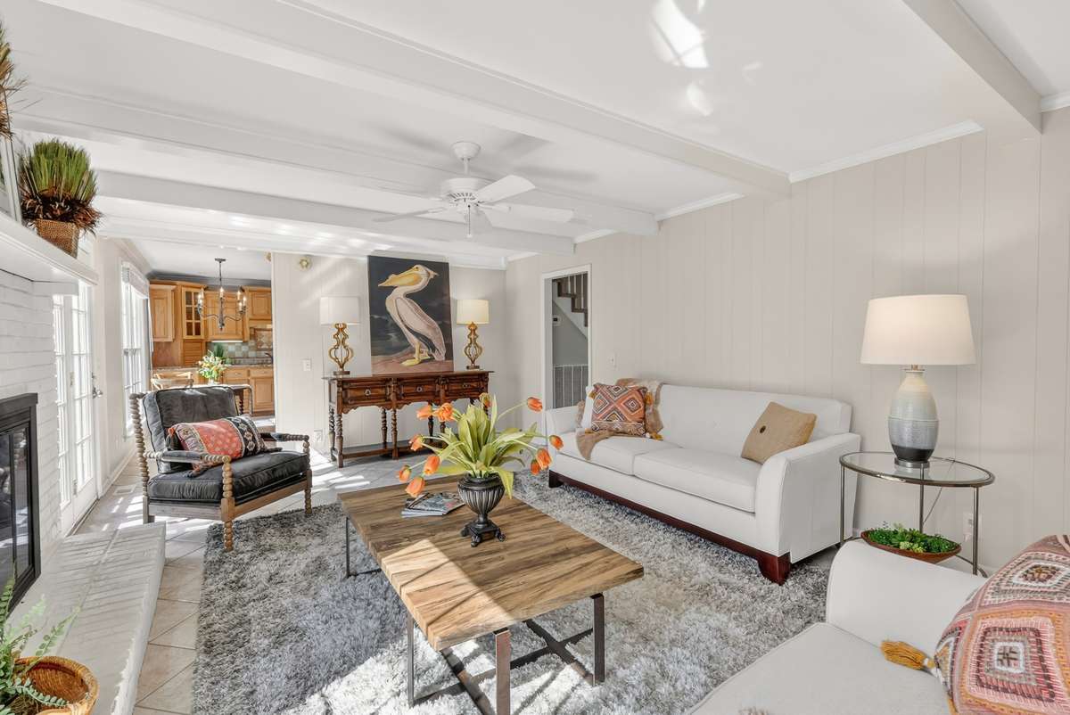 This bright and cheerful great room has lots of charm and character with the painted brick fireplace, paneling and beams.