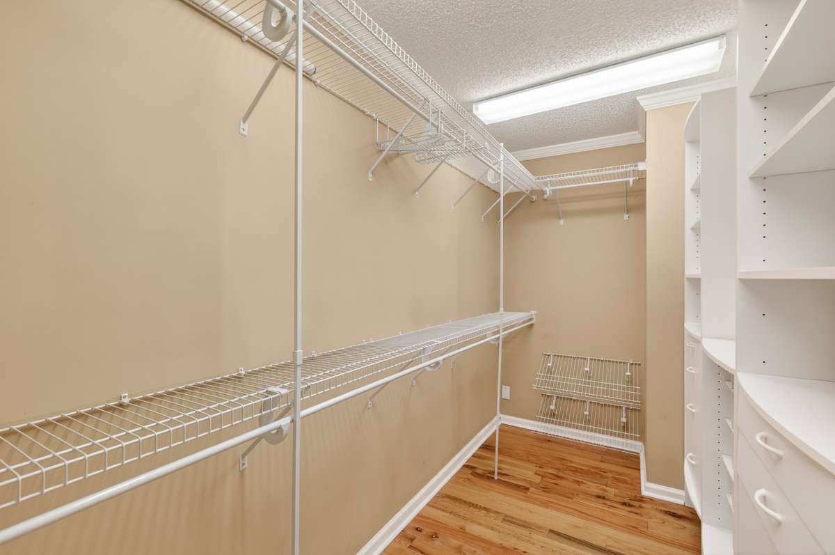 Large master suite closet with built-ins and wood flooring