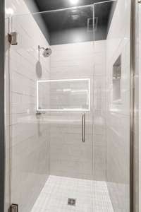 Modern walk-in shower featuring frameless glass, classic subway tile, and a built-in niche.