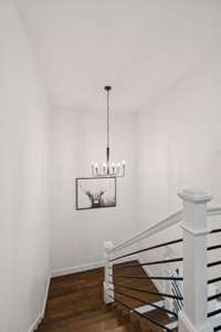 Elegant staircase with wood treads and white spindles connects the main level to the upstairs living areas.