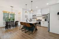 Chef’s kitchen with gas range, vent hood, expansive island, and beautiful cabinetry. Open to living and dining areas, it’s ideal for entertaining and everyday meals with family and friends.