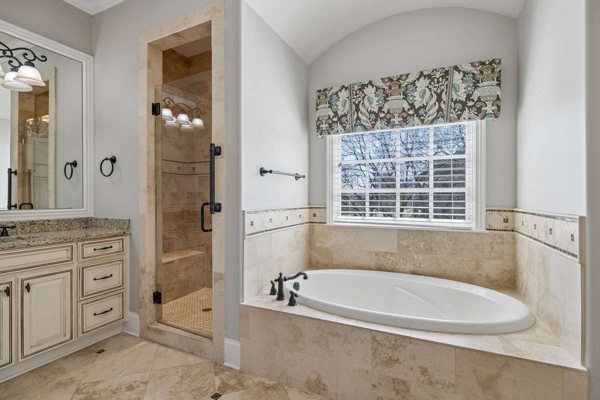 Primary bath features two vanity areas and separate tub and shower with seating area.