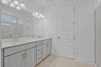 Primary bath features double vanities, quartz countertops, ceramic tile floors, and tiled walk-in shower or separate shower and tub.