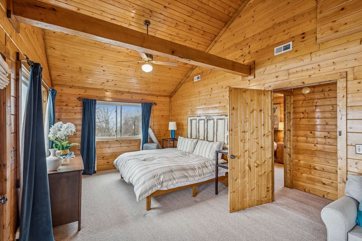 Large primary bedroom with cathedral ceilings, beams, and space for a sitting area or second bed.
