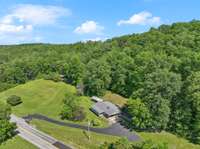 This breathtaking aerial view showcases the property's wooded privacy in the rear — a peaceful natural buffer that also leads to a scenic hilltop, offering a potential additional building site with endless possibilities.