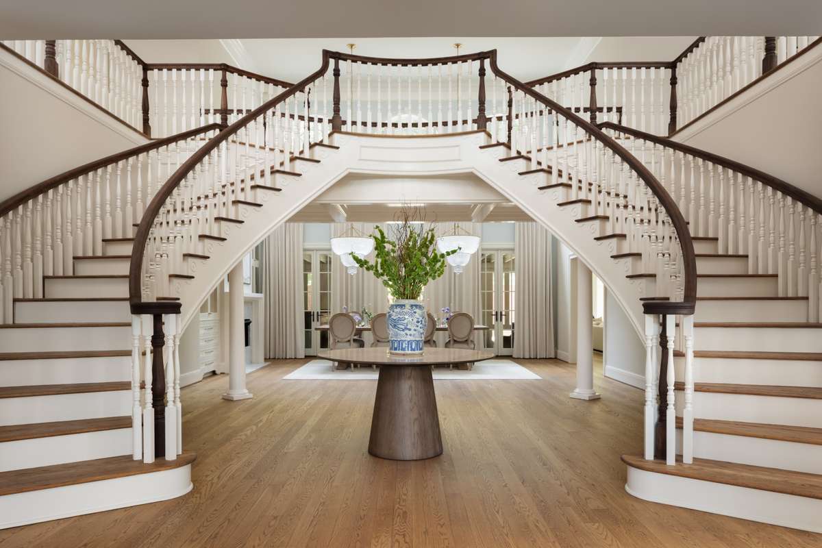 Two-story foyer with dual curved staircases introducing the home’s scale