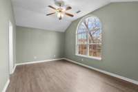 The primary bedroom is a serene retreat with a vaulted ceiling and grand double window topped by an elegant Palladian window that fills the space with natural light.