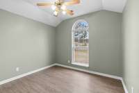 Bedroom two boasts an impressive vaulted ceiling, luxury vinyl flooring, a full closet, and a bright window crowned by a Palladian window that adds architectural elegance.