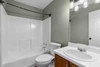 The hall bath includes luxury vinyl flooring, a tub/shower combination, chrome fixtures, a chic
matte black light fixture, and warm wood cabinetry—offering a polished and modern feel.