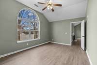 Luxury vinyl flooring, a ceiling fan, and a spacious walk-in closet further enhance the room’s comfort and refinement.