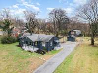 An Aerial view showcasing the entire property, 3 Bedroom 1 Bath Home, a 1 car detached garage and a detached 2 car garage with upstairs finished studio space w/kit all on a spacious lot w/ a long driveway, ample parking, & mature trees!