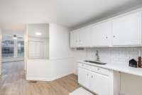 Additional view of the finished studio space above the garage showing the flexible layout and built-in kitchenette/utility area with white cabinetry, subway tile backsplash, and sink.