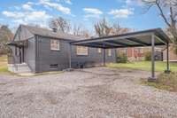 Another rear view highlighting the expansive parking area and large covered carport