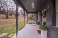 This home features a welcoming covered front porch with decorative ironwork and a relaxing porch swing
