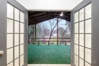 Covered rear deck off the finished studio space featuring double French doors and a spacious, sheltered outdoor area, perfect for relaxing or entertaining