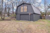 Detached garage with stylish modern exterior and a finished studio space with kitchenette, full bath and utilities, offering excellent flexibility for guests or a private home office