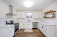 Bright, updated kitchen featuring NEW white shaker cabinetry with matte black hardware, sleek white quartz countertops, and a classic white subway tile backsplash.