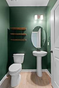 Powder room for guests with pedestal sink and floating shelves.  Located right off of the foyer area.