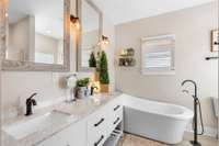 Primary bathroom with modern lighting, soaking tub, separate shower, and double vanities, perfect for relaxing!