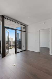 Floor-to-ceiling glass opens to a private balcony with sweeping city views—bright, modern living in the heart of Nashville.