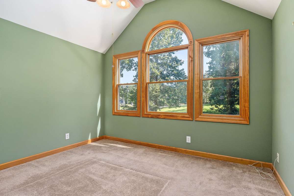 The front upstairs bedroom features a vaulted ceiling, three large windows, and a view of the front yard.