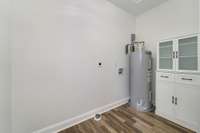 Large utility room with water heater, W/D hookups, and cabinet