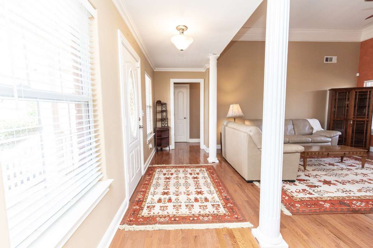 Step into this beautiful foyer with hardwood floors, soaring ceilings & columns