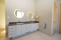 Primary bathroom double vanity with quartz countertops, custom cabinetry, and integrated lighting.