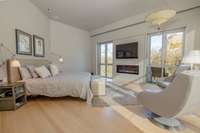 Primary bedroom featuring floor-to-ceiling windows, private balcony access, and a calm, light-filled layout with integrated fireplace.