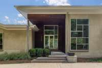 Contemporary front elevation showcasing clean lines, limestone cladding, deep overhangs, and a sheltered entry inspired by Japanese Pavilion design.