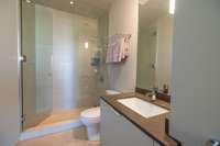 En-suite bath with glass-enclosed shower, Toto fixtures, quartz vanity, and clean-lined contemporary finishes.