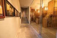 Glass-enclosed wine cellar entry with gallery-style approach, slate flooring, and curated display walls.