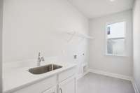 Durable tile flooring and a handy laundry sink make this laundry room a practical, easy-to-use space for everyday tasks.