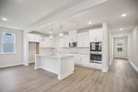 With its crisp white cabinetry, durable quartz countertops, and stylish herringbone tile backsplash, the gourmet kitchen offers both beauty and functionality.