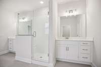 Experience spa-like luxury in the owner’s bath, featuring a tiled walk-in shower with a built-in seat, soaking tub, and separate vanities with quartz countertops.