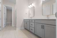Primary bath with designer mirrors, double sinks, quartz countertops and 12x24 tile flooring