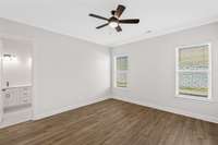 The primary bedroom has two windows of the back, mohawk flooring and a ceiling fan.