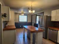 Kitchen has Extra Cabinets and an Island for Food Preparation & Serving.